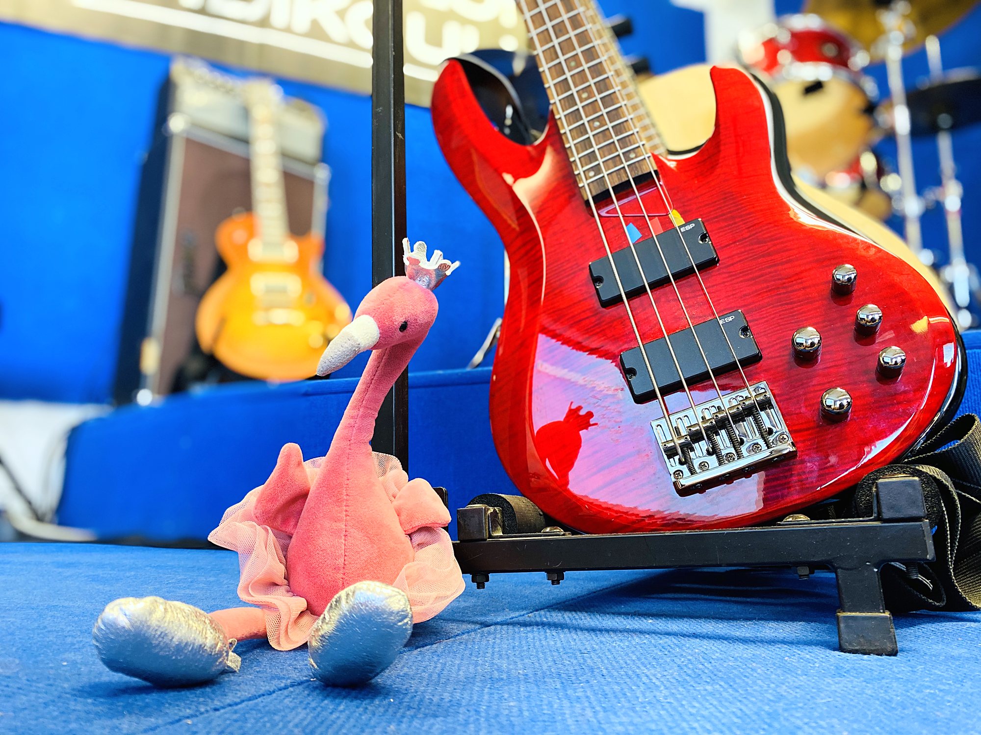 Punainen sähköbasso ja flamingopehmolelu bändikoulun lavalla